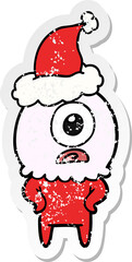 distressed sticker cartoon of a cyclops alien spaceman wearing santa hat