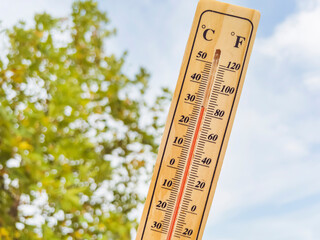 Wooden thermometer with red measuring liquid on a mountain background 