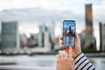 A person takes a mobile photo of Manhattan skyline in New York City, United States.