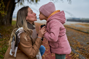 Fototapeta premium In candid pauses, the mother and daughter share hugs and kisses, creating cherished memories amid their walk.