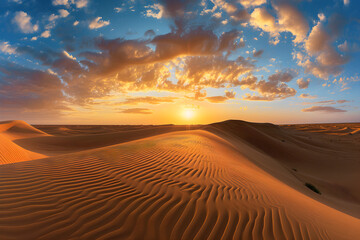 Sunset over the arid landscape of the desert, showcasing golden sand dunes under an orange sky during a hot summer evening