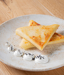 pancakes with creamy sauce on a light plate on a wooden table