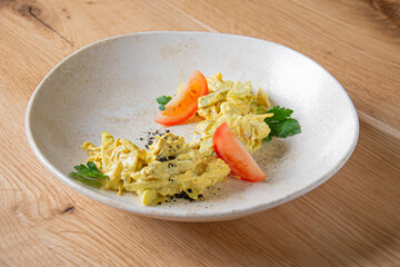Scrambled omelette with tomato slices on a white plate