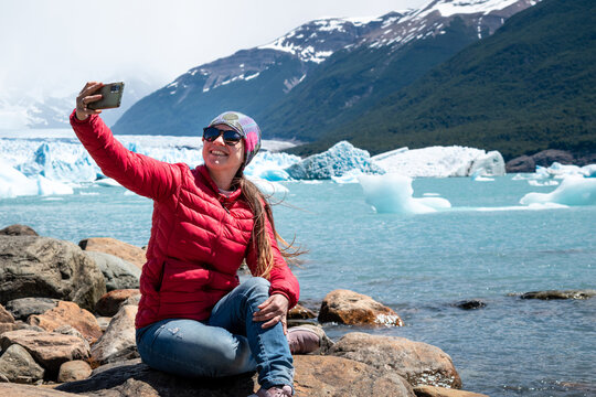 Mujer turista tomándose una selfie con el Glaciar Perito Moreno de fondo, en la Patagonia Argentina