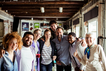 Diverse and multigenerational group of people looking at the camera while working in a startup company office