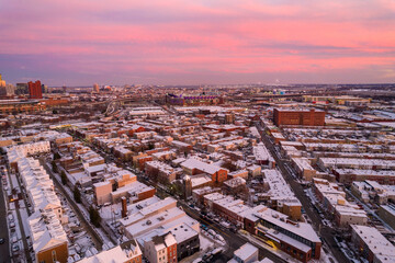 Fototapeta na wymiar Drone View of Baltimore City Houses with Snow Covered Roofs at Sunset with Orange and Pink Skies