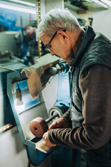 A senior cobbler is using shoe making tool for fixing footwear.