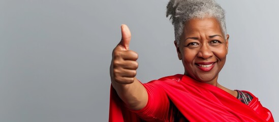 An African American middle-aged woman in a superhero outfit gives a thumbs up and looks at the camera with a successful expression.