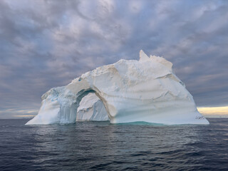 A huge high breakaway glacier drifts in the southern ocean off the coast of Antarctica at sunset,...