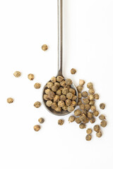 Green peppercorns in iron spoon on white background. Organic spice. Dry green pepper grain. Top view 