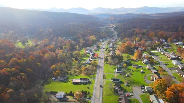 Aerial view of the small town surrounded by the forest in the mountain in autumn morning.
