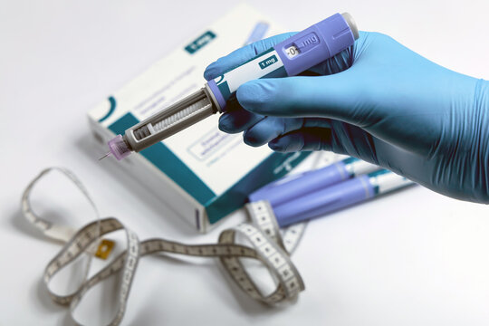 Hands in surgical gloves holding Ozempic Insulin injection pen for diabetics.