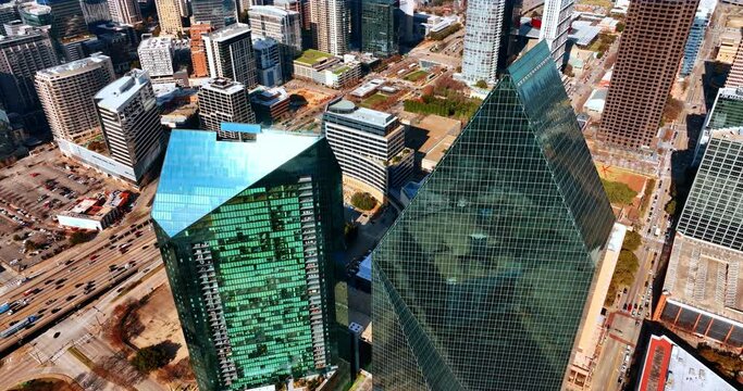 Sharp roofs of the mirror skyscrapers reflecting sunlight. Drone footage above the buildings in the uptown of Dallas, Texas, USA.
