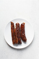 Top view of chinese sausage in a white plate, overhead view of lap cheong sausage on white background