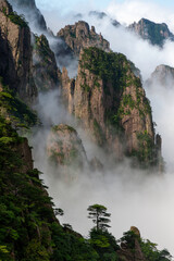 Misty clouds hover around Cloud Dispersing Pavillion's Boot Rock in the Yellow Mountains of China.