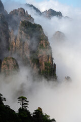 Fototapeta premium Misty clouds hover around Cloud Dispersing Pavillion's Boot Rock in the Yellow Mountains of China.