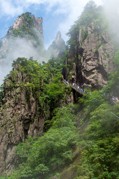 Tourists view thr Huangshan Yellow Mountains from a staircase along the face of a rock wall.