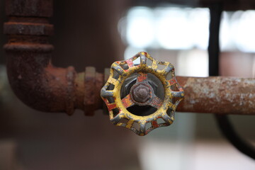 Rusty, corroded iron pipe with a yellow wheel, old factory technology, steampunk elements on lost place, concept of change
