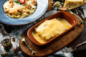 Delicious lasagna with cheese and meat in plate on wooden background with napkin. Italian food, top view
