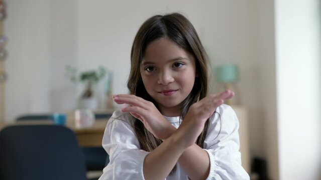 One little girl making an X with arms in rejection. Child saying NO