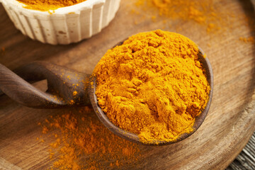 Ground turmeric root on a spoon on a table