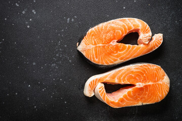 Raw fish, fresh salmon steaks at black background.