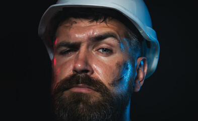 Closeup portrait of construction worker in hard hat. Serious male builder, architect or engineer in protective hardhat. Hard work. Bearded miner or industrial worker with dirty face in safety helmet.