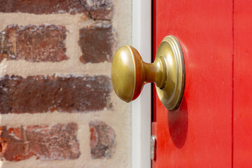 Selective focus of old and classic doorknob on red wood, Copper handle on a door that is turned to release the latch, Door opener holder for the main enter house with brick block wall as background.