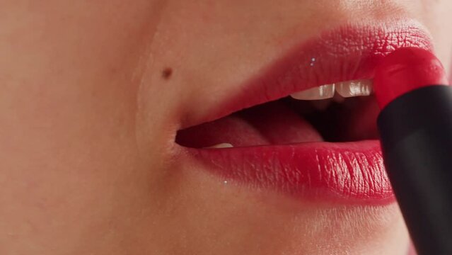 Young woman make-Up with a pink Lipstick on her lips close-up. Shooting of woman applying lipstick