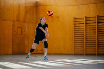 A volleyball player is passing the ball and practicing on court.