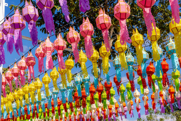Fototapeta premium Yi Peng festival concept, Celebrated annually Loy Krathong in November, Multi colourful of lanna lanterns with blue clear sky as background, Traditional handicraft of lamps in the Northern of Thailand