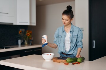 Attractive Caucasian Woman in Modern Kitchen, Enjoying Healthy Breakfast with Fresh Fruit and Juice, Looking Happy and Casual while using Smartphone.