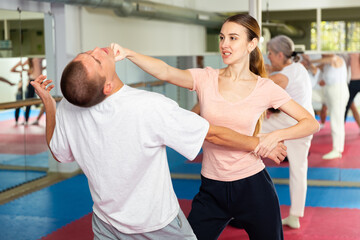 Young woman exercising chin strike on man during self-protection training.