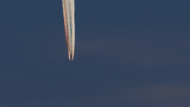 Jet leaving colorful contrails in the dusk sky