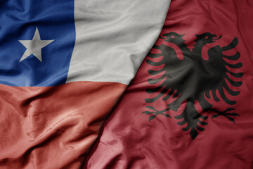big waving national colorful flag of albania and national flag of chile .