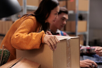 Warehouse employees holding packed package and creating invoice on laptop. Storehouse asian...
