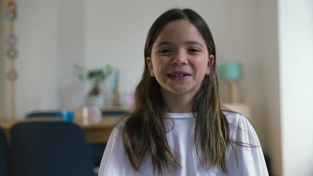 One happy little girl smiling and laughing at camera standing indoor at living-room, close-up face of an 8 year old portrait