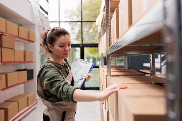 Warehouse supervisor checking cardboard boxes barcode, preparing customers orders in storage room. Caucasian worker managing merchandise holding clipboard with supply details in storehouse