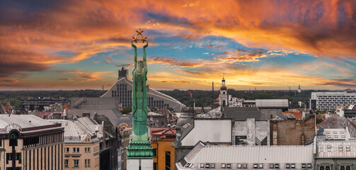 Beautiful sunrise view over Riga by the statue of liberty - Milda in Latvia. The monument of freedom. - obrazy, fototapety, plakaty