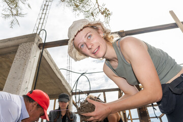 Portrait of volunteer building a Mud House for an Environmentally Conscious Community