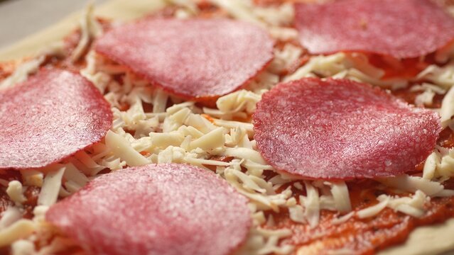 Raw Mushrooms with Salami and Cheese on Pizza Dough. Close-up, shallow dof. - Powered by Adobe