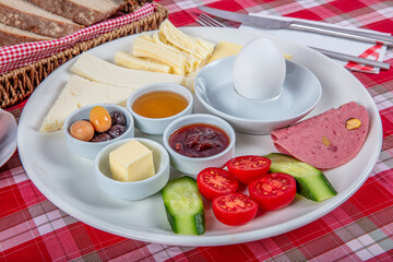 Turkish Cuisine Breakfast Plate. White breakfast plate with sliced cherry tomatoes, cucumber and boiled egg with on wooden table.