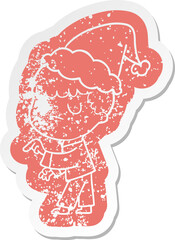 cartoon distressed sticker of a grumpy boy wearing santa hat