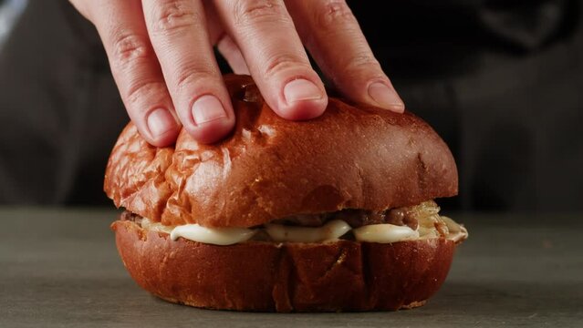 American fat smash burger with bacon slices and cheese on grill close-up macro. Beef or pork cutlet smashing by burger press. The chef in kitchen of the restaurant making cutlets for burgers - smash