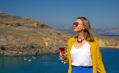 Woman in sunglasses with red wine on the balcony.
