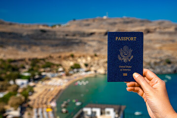 Woman holding USA passport against the backdrop of a tropical country.