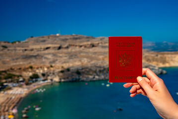 Woman holding Russian passport against the backdrop of a tropical country.