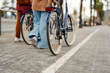 Fototapeta premium Cropped picture of friends pushing bikes on the street.