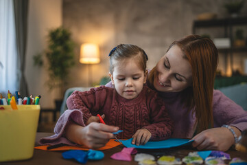 Mother and daughter toddler child play at home craft in room