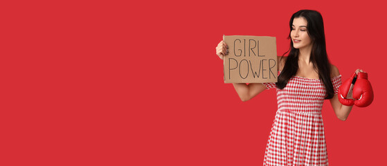 Young woman holding boxing gloves and paper with slogan GIRL POWER on red background with space for...